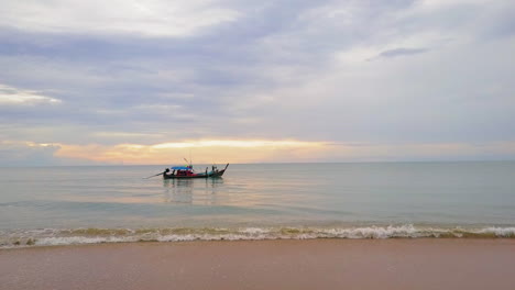 Sonnenuntergang-Vom-Strand-Aus-Gesehen-Mit-Einem-Longtail-Boot-Auf-Dem-Wasser