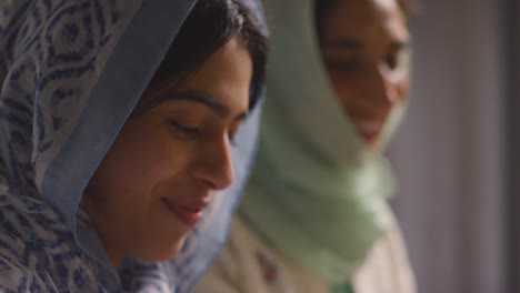 muslim mother and daughter sitting around table at home eating meal together