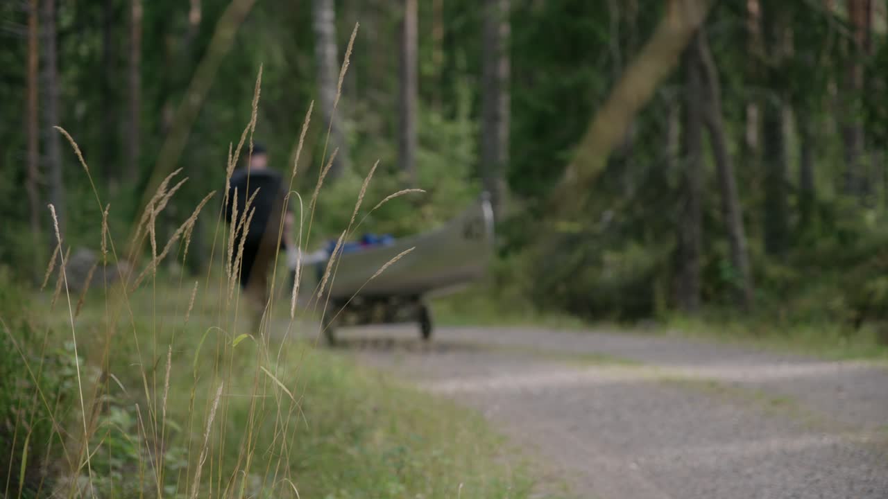 잔디가 있는 푸른 숲의 자갈길을 따라 바퀴로 카약을 걷고 안내하는 등산객