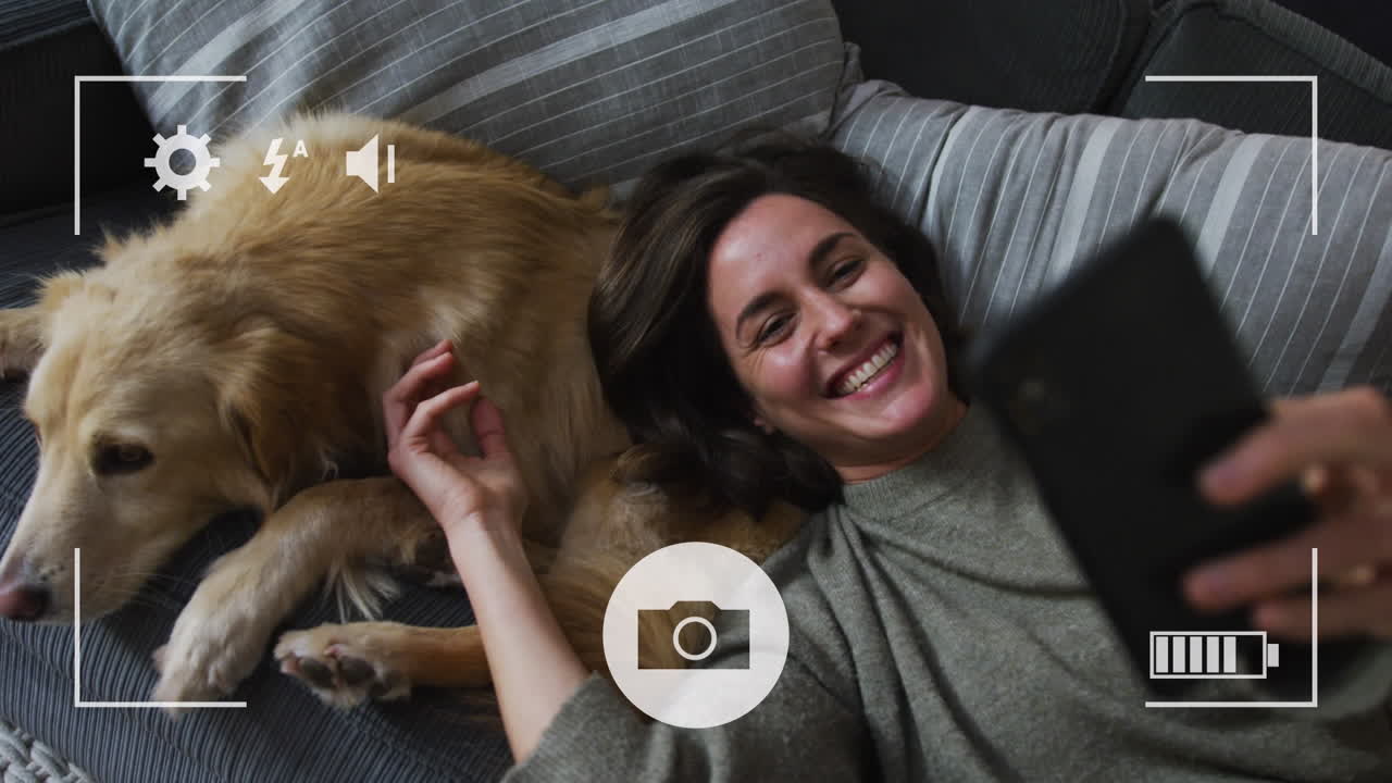 카메라 인터페이스와 백인 여성이 소파에서 개와 셀카를 찍고 있습니다.