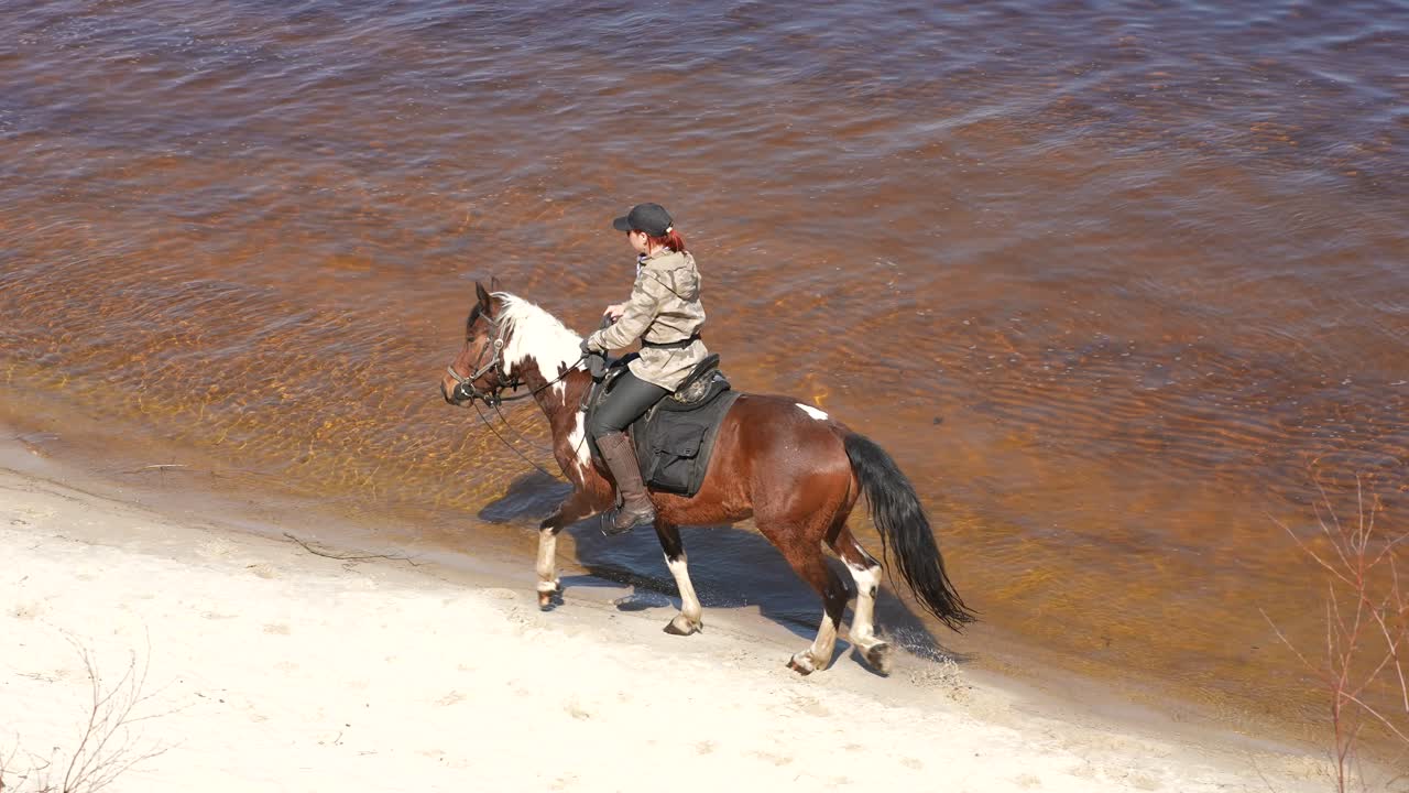 mujer a caballo a lo largo de una orilla del río