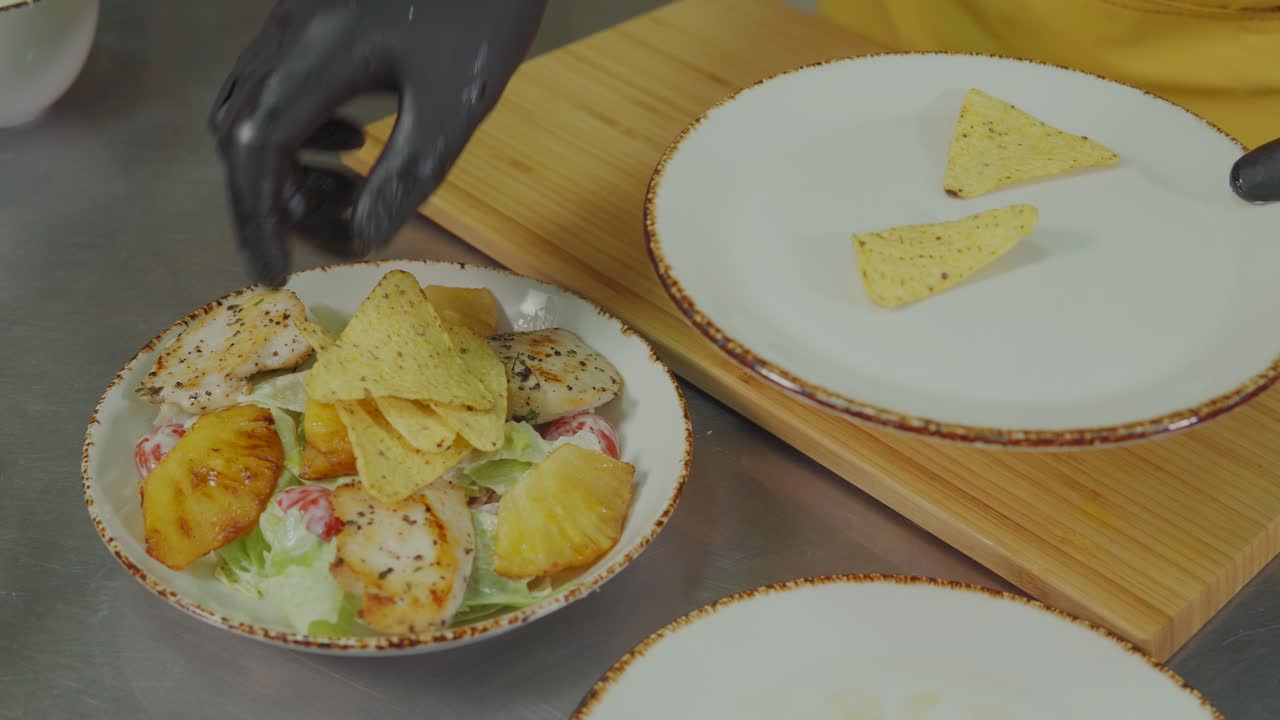 chef preparando una ensalada de pollo y piña con chips de tortilla