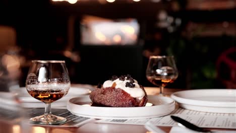 romantic dinner scene with two glasses of dessert liquor and a pastry to share with a fire burning in the background