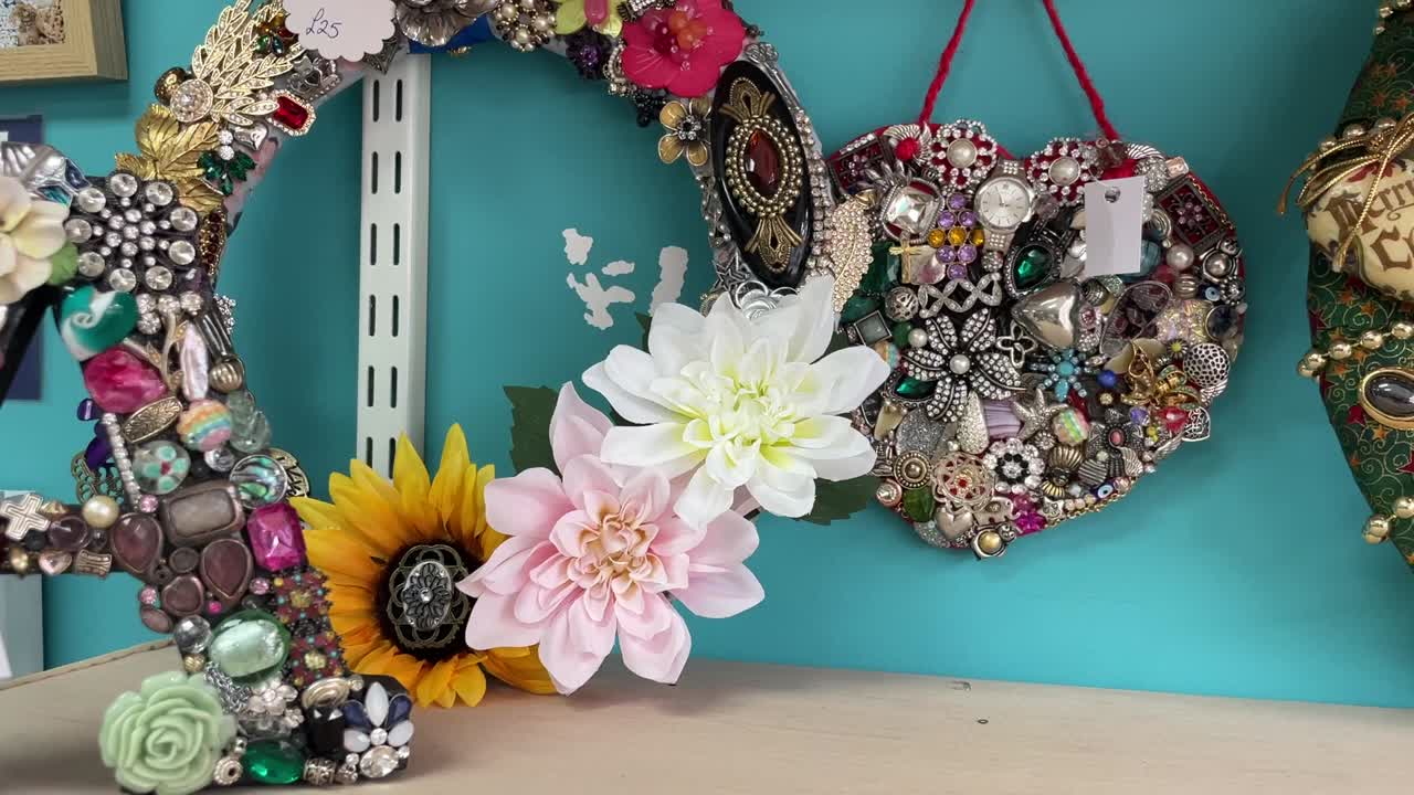 A collection of handmade decorative wreaths featuring intricate details, colorful flowers, and vintage jewelry. These unique designs showcase creativity and craftsmanship for festive occasions.