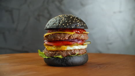 Burger-or-hamburger-with-black-bread-on-a-blurred-background-of-leaves