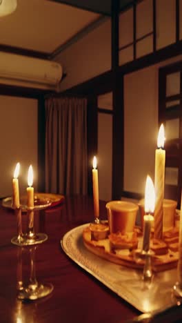 birthday cake adorned with lit candles resting on a table in a traditional room, open sliding doors revealing a serene dusk view of snow capped mountains