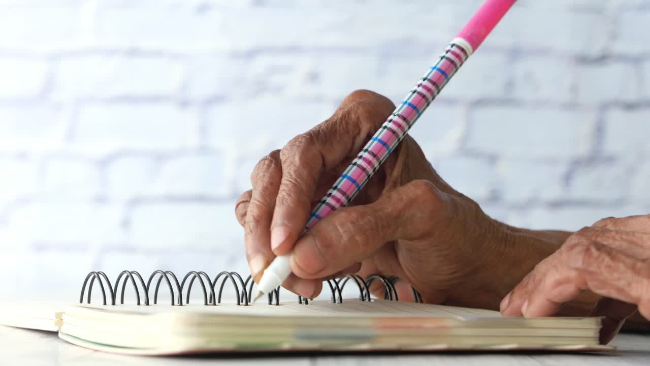 Elderly hands writing in a notebook