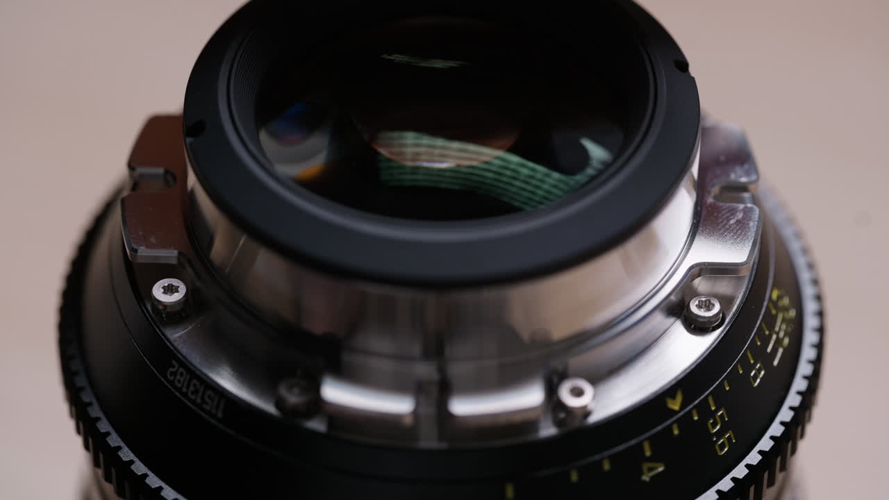 Close-up of tweezers carefully placing a tiny screw into a PL mount on a cinema lens. Precise and delicate assembly process during lens mount conversion on a wooden desk