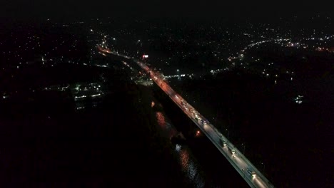 4K-Drohnenvideo-Von-Fahrzeugen,-Die-Nachts-Auf-Einer-Brücke-über-Einen-Fluss-Fahren