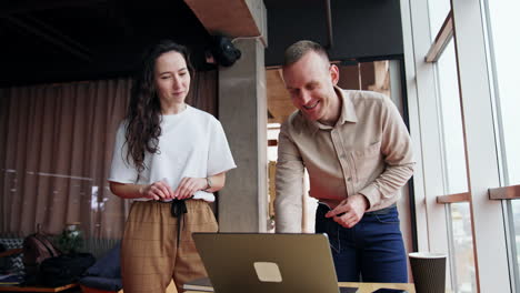 male and female colleagues collaborating in the office. workmates look at laptop discussing it. low angle view.