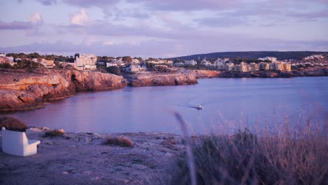 Bellas-Imágenes-En-Cámara-Lenta-De-4k-De-La-Costa-De-Mallorca-Mientras-Se-Pone-El-Sol-Con-Un-Barco-A-Motor-Navegando-Por