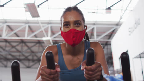 Mujer-De-Raza-Mixta-Con-Mascarilla-Haciendo-Ejercicio-En-El-Gimnasio