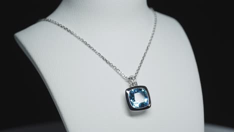 blue gemstone on a necklace on a rotating bust