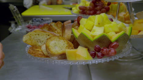 persons hands adjusting a fruit platter display bowl in a restaurant