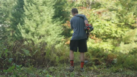 Landscaper using weed whacker on ferns and vegetation (Slow Motion 4k 30p)