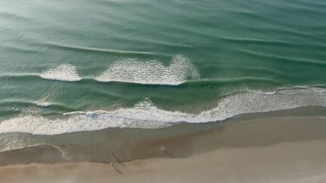 Schöne-4K-Strandantenne---Eine-Vogelperspektive-Von-Meereswellen,-Die-Bei-Sonnenaufgang-Von-Oben-Gegen-Einen-Strand-Schlagen