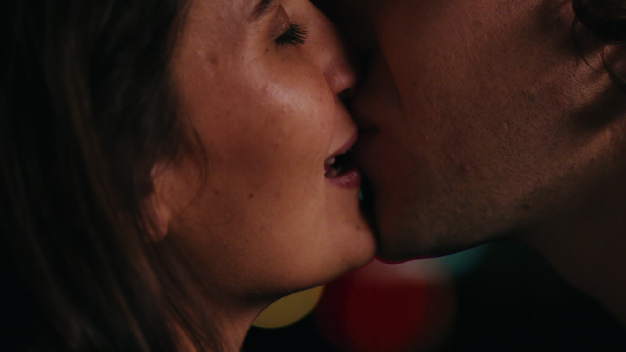 da vicino una giovane coppia caucasica che si bacia sul tetto di notte godendo di una relazione romantica abbracciandosi in una tranquilla serata urbana guardando le splendide luci della città