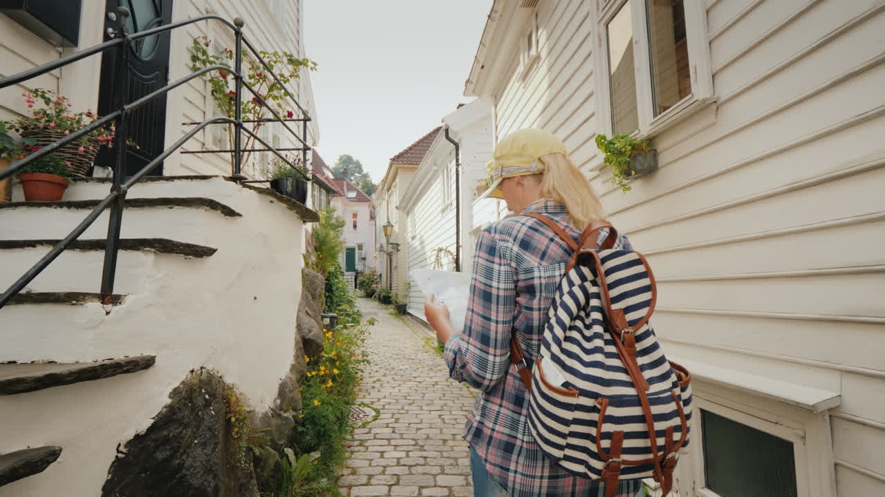 turista con un mapa en sus manos caminando por las estrechas calles de bergen en noruega vacaciones en s