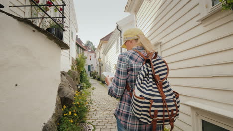Tourist-With-A-Map-In-Her-Hands-Walking-Through-The-Narrow-Streets-Of-Bergen-In-Norway-Holidays-In-S