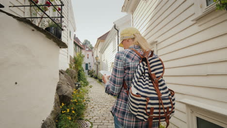 turista com um mapa nas mãos caminhando pelas ruas estreitas de bergen na noruega feriados em s