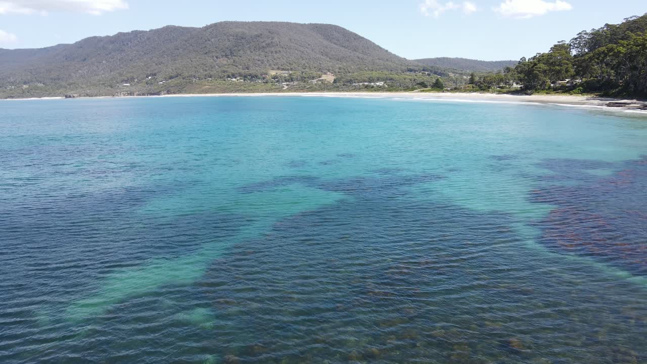 화창한 여름날 산을 드러내기 위해 열대 푸른 물 위로 드론 공중 팬