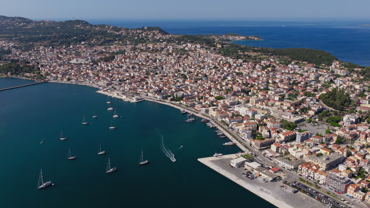 Panoramic drone shot of Argostoli city on a sunny summer day, revealing the town’s unique layout, busy waterfront, and surrounding mountains under a clear blue sky