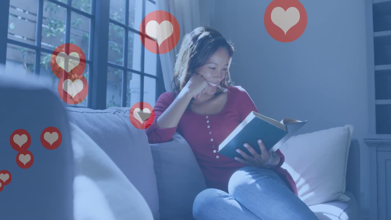 animación de iconos de corazones digitales sobre una mujer leyendo un libro y sonriendo en casa