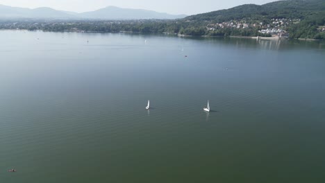 línea de costa del lago sereno en las montañas beskid, rodeado de vegetación durante un día de verano - vista aérea 4k