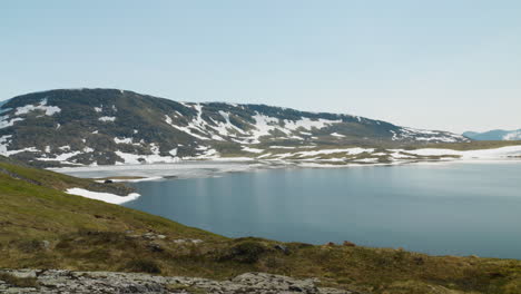 small lake on a top of a mountain coverd with snow at summer