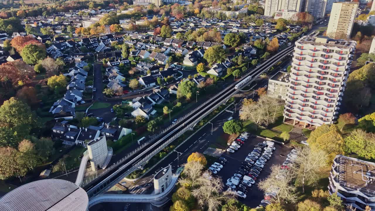 Ilmakuva droonilla kuvattuna junasta, joka on saapumassa La Poterien metroasemalle Rennesissä. Näyttää modernin, korotetun radan ja aseman, jota ympäröivät syksyiset puut. Ihanteellinen kaupunkiliikenteen konsepteihin, Ranska