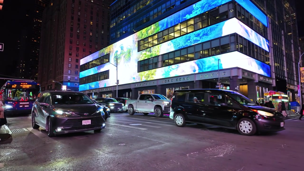 New York, USA, 5 febbraio 2026: Incrocio cittadino notturno con grandi cartelloni digitali illuminati di blu