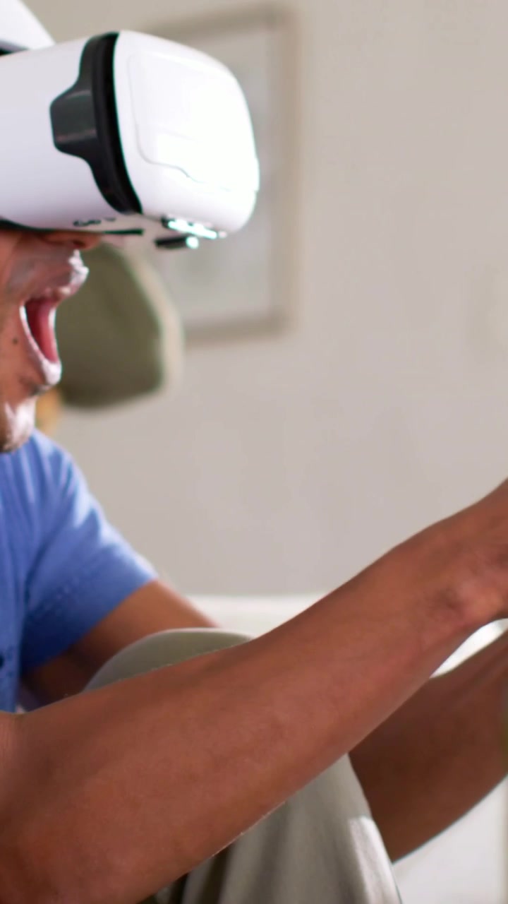 Video verticale: Uomo in polo blu che indossa un visore VR bianco e gioca a casa usando un controller, con spazio per il testo.