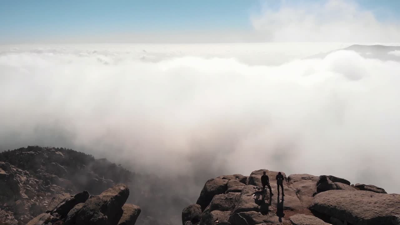 vista aérea sobre la montaña rocosa con nubes en el fondo durante el día