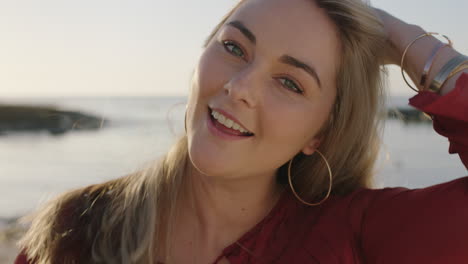 Primer-Plano-Retrato-De-Una-Hermosa-Joven-Rubia-En-La-Playa-Sonriendo-Alegre-Pasa-La-Mano-Por-El-Cabello-Sintiéndose-Segura