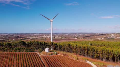 wind turbine next to an old windmill, aerial flying backwards