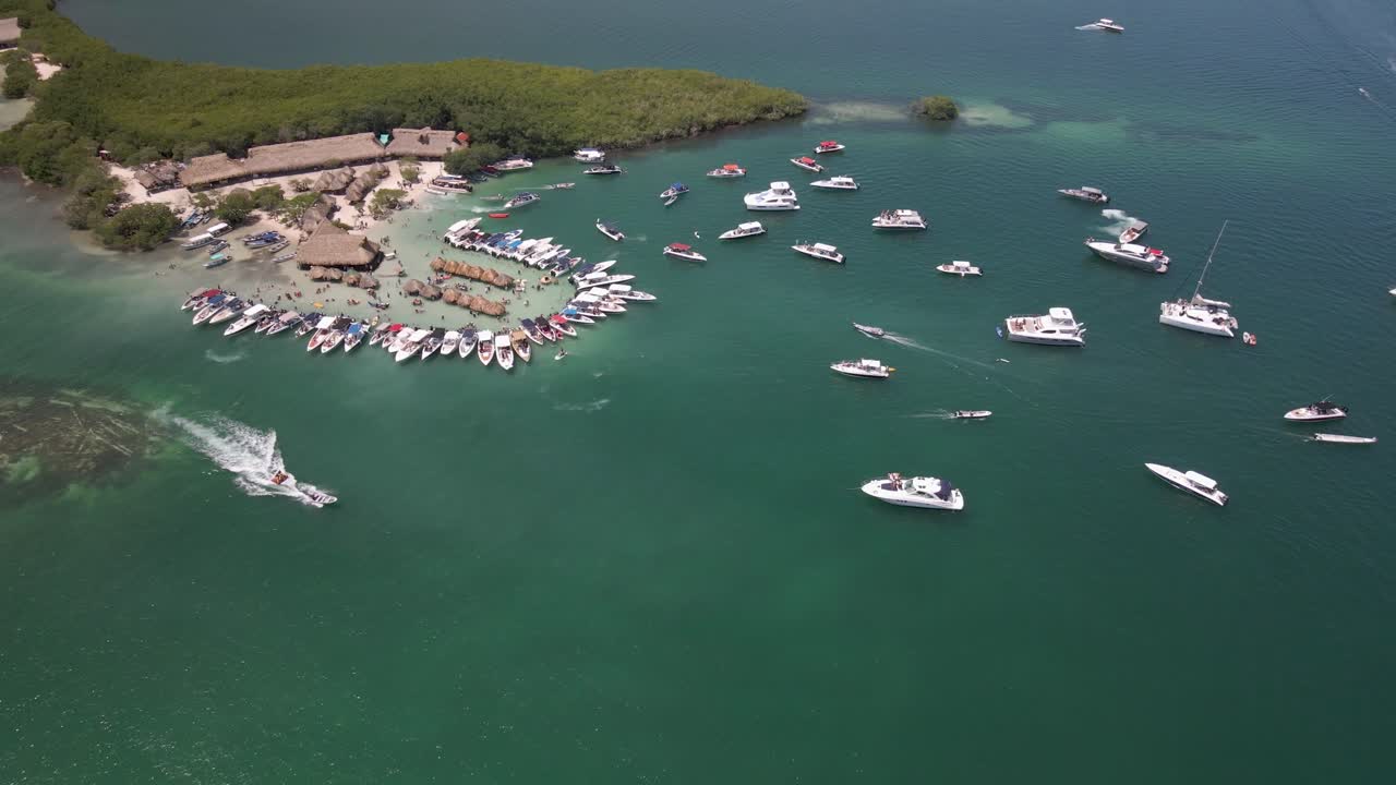 Cholon Island aerial video, tilting down moving towards the boats and tiki huts. Shot this aerial video mid-day at the busiest time while everyone is partying and yachts are surrounding the island.
