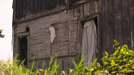 Wind-Weht-In-Laken,-Die-Die-Eingänge-Eines-Kaputten,-Verlassenen-Hauses-Bedecken