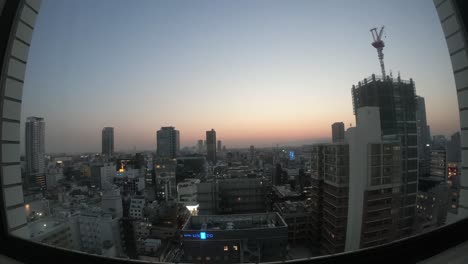 ultra-wide time lapse of the osaka skyline buildings going from day to night, unizo hotel sign visible, locked speed-up shot