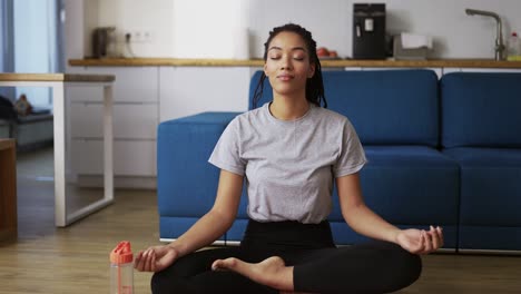 african american woman is sitting lotus pose on yoga mat floor closed eyes