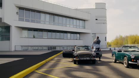 vintage cars in front of modern building