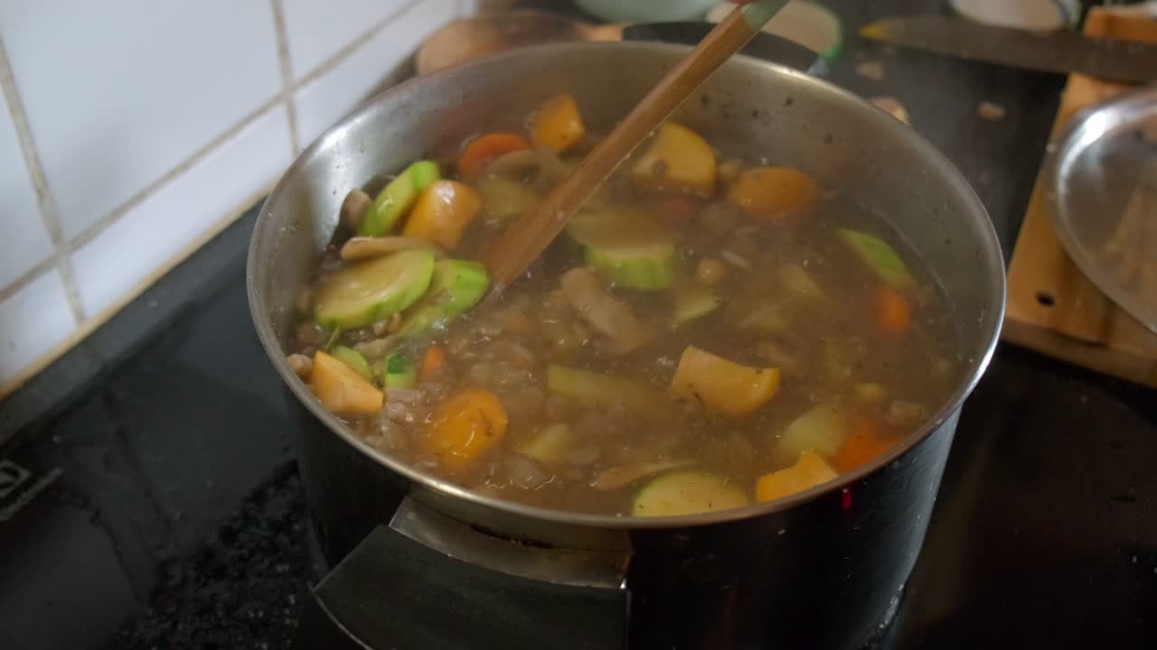 vista de una sopa de verduras siendo agitada en una olla de vapor en cámara lenta 4k