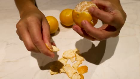 hands peeling an orange on a marble surface