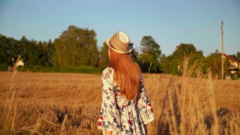 Stunning-HD-footage-of-a-beautiful-young-woman-in-a-dress,-wearing-a-knitted-hat-and-red-lipstick,-joyfully-walking-through-a-wheat-field