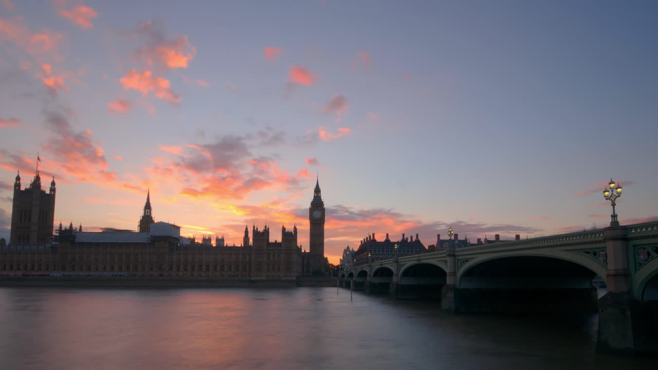 Evening hyperlapse glides past Westminster Bridge and luminous Big Ben as Houses of Parliament rise in golden hour, smooth Thames waters mirror dramatic clouds and fading sunlight