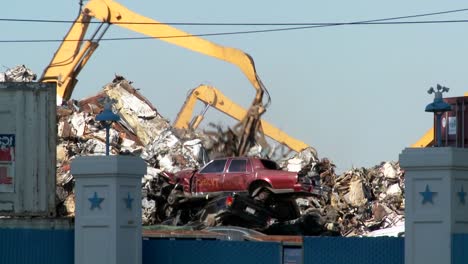 cranes lift and move scrap metal around abandoned and destroyed cars in a junkyard or scrap metal yard 3