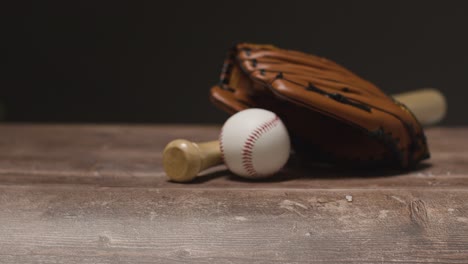 close up studio baseball still life with wooden bat and ball in catchers mitt on wooden floor 2