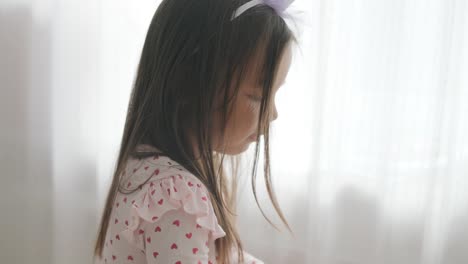 young girl sitting at a table, drawing with colorful crayons. ideal for themes of creativity, childhood development, learning, and art activities in a cozy indoor setting.