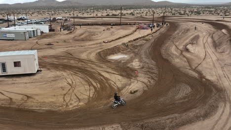 motorcycles racing on an off-road dirt racetrack and making high jumps - aerial flyover