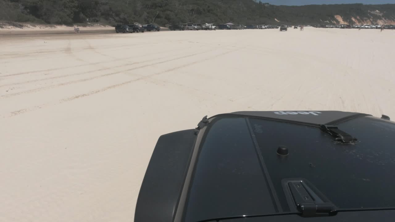 다른 4x4 자동차로 붐비는 백사장에서 검은색 지프 드라이브