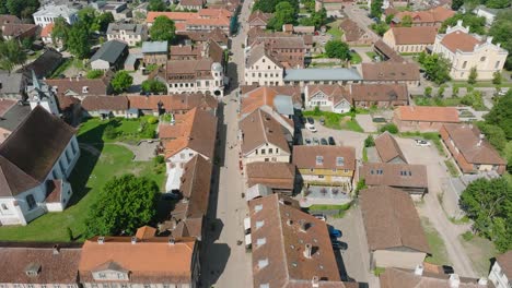 aerial establishing view of kuldiga old town , houses with red roof tiles, sunny summer day, travel destination, wide drone shot moving forward, tilt up